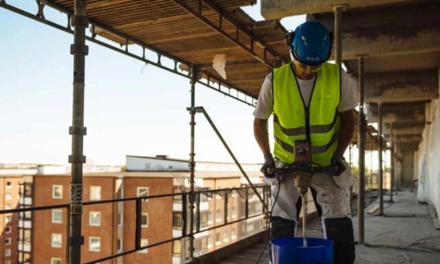 Betongrenovering av loftgång med arbetare som applicerar ytskydd på utvändig betongyta